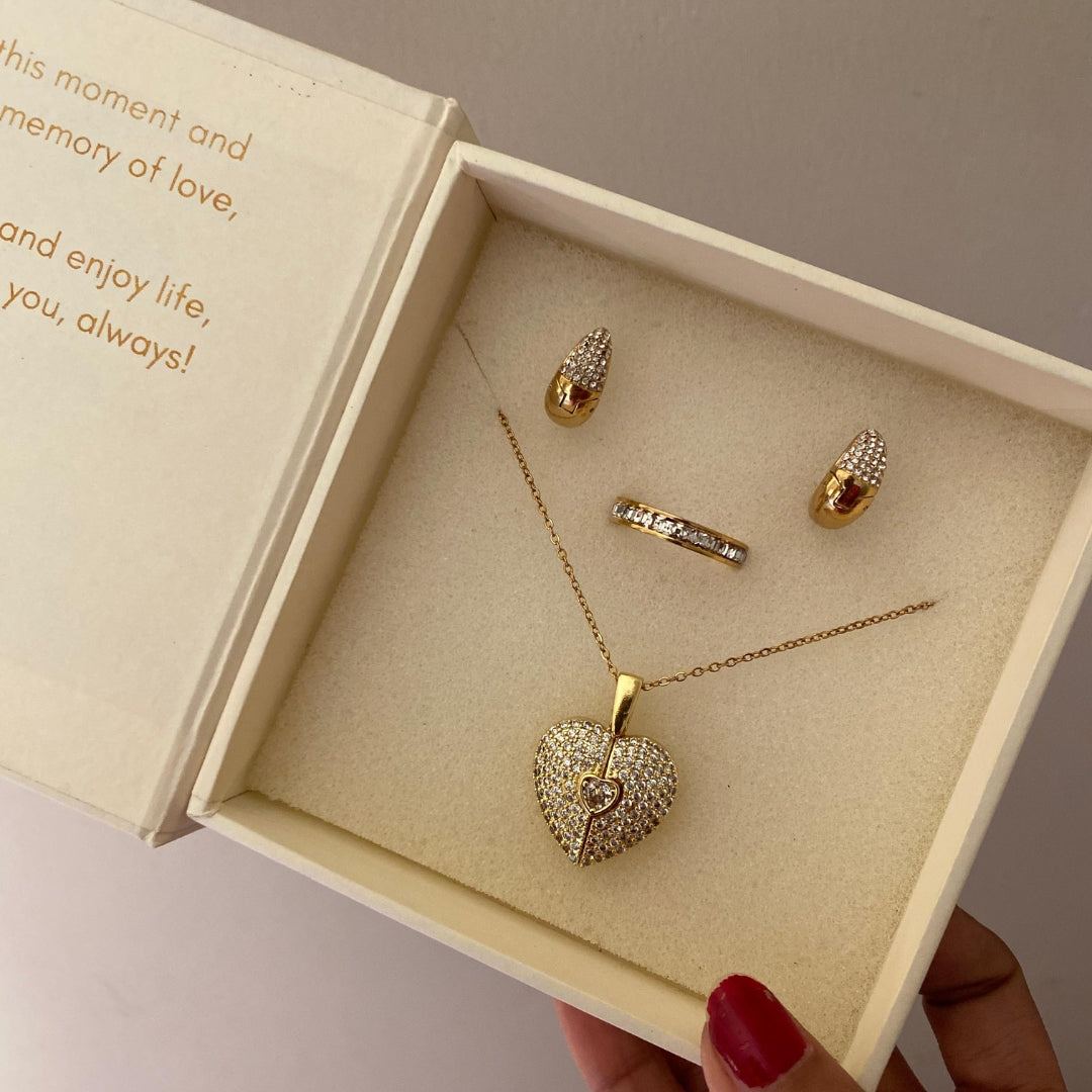 Gold-tone chain necklace laid flat with a puffed pavé heart and flower charm