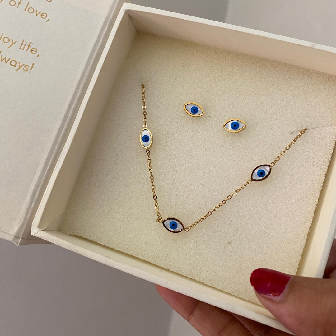 Close-up of a blue and white eye motif in a gold-tone frame on a necklace and stud