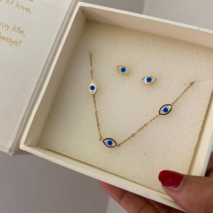 Close-up of a blue and white eye motif in a gold-tone frame on a necklace and stud