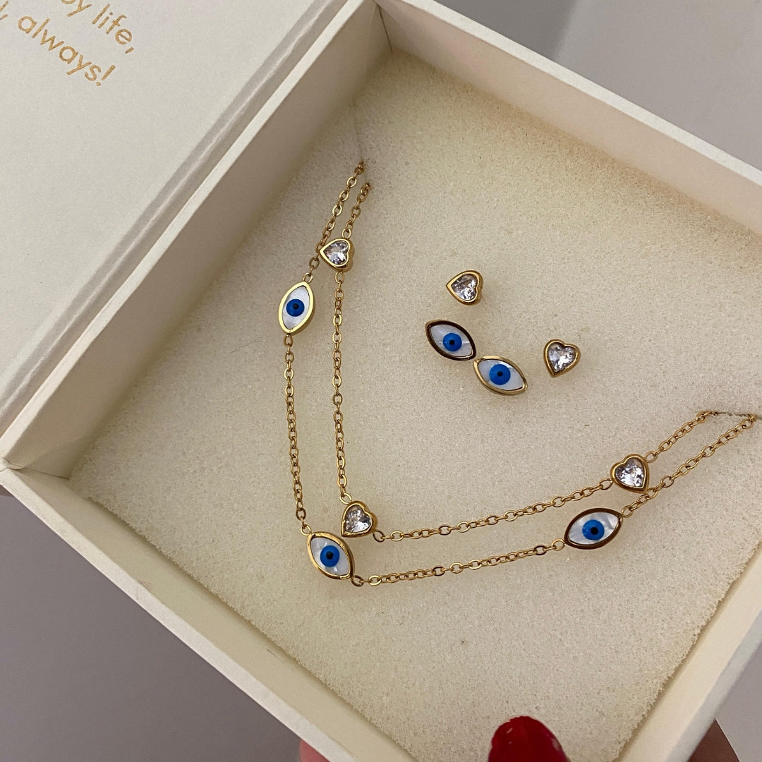 Gold-tone evil eye necklace with extender chain and matching eye studs laid flat