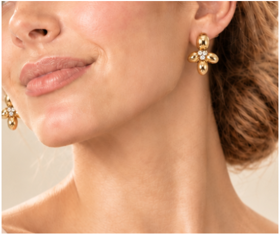 Close-up of three small clear stones at the center of a gold-tone four-petal flower earring