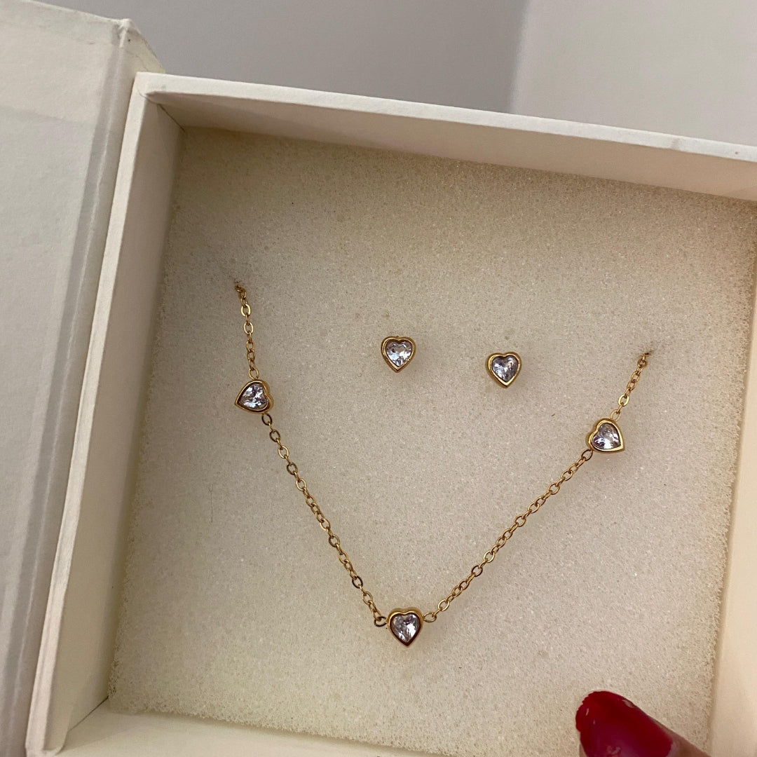 Gold-tone heart station necklace with extender chain and matching heart studs laid flat