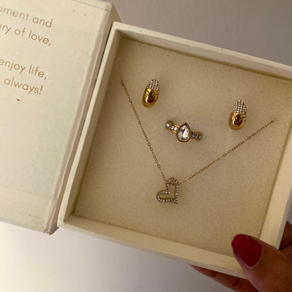 Gold-tone link chain necklace laid flat with a slanted open heart pendant