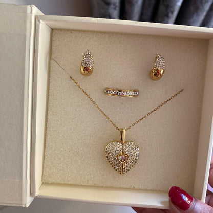  Close-up of a clear stone covered heart pendant with a small textured flower charm