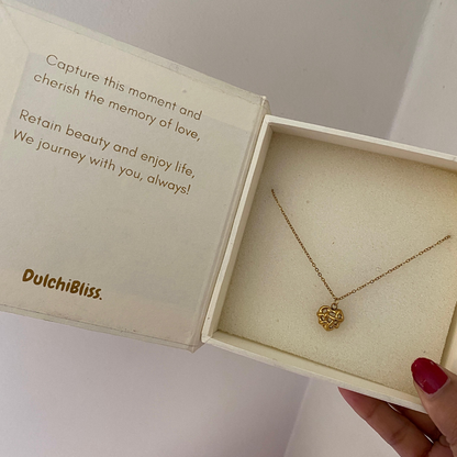 Sculpted heart necklace laid flat showing the small pendant and fine gold-tone chain