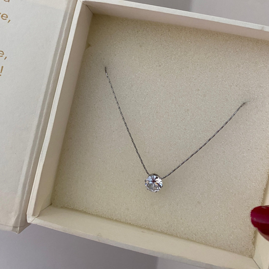 Close-up of a single round clear stone on a fine silver-tone stainless steel necklace