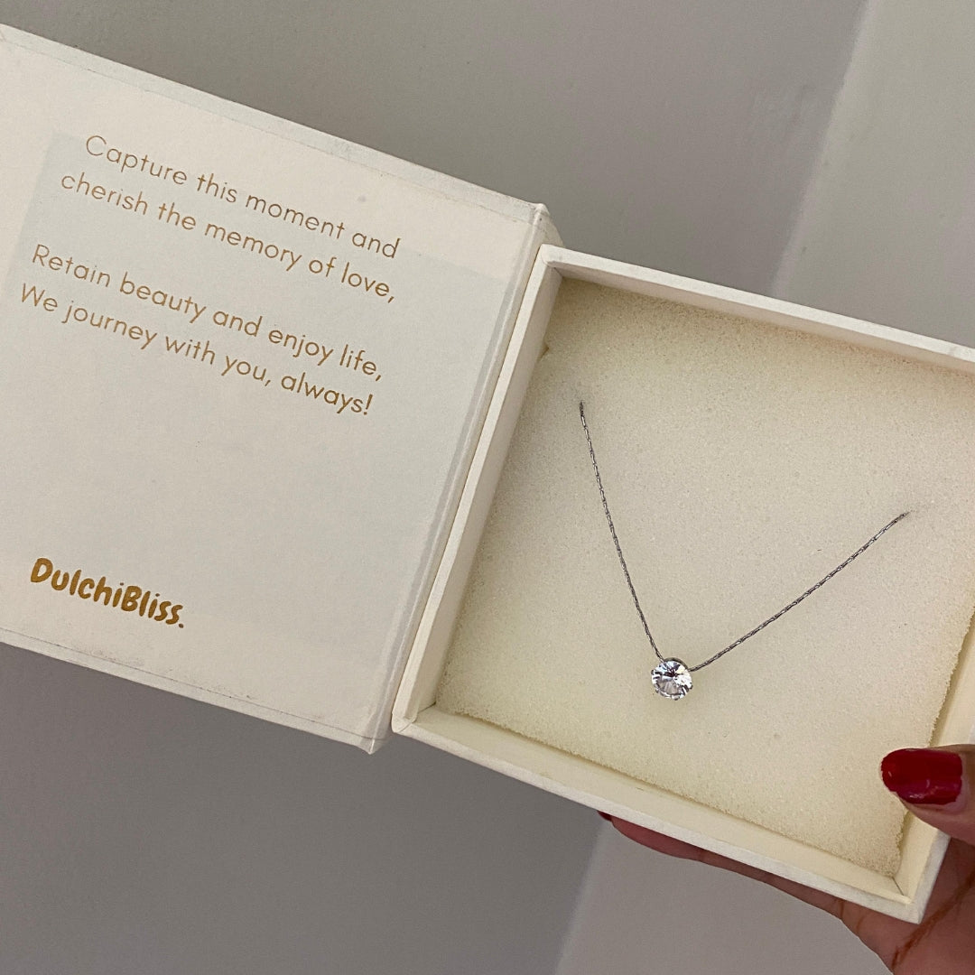 Silver-tone solitaire necklace laid flat showing the chain and round clear stone