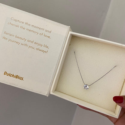 Silver-tone solitaire necklace laid flat showing the chain and round clear stone