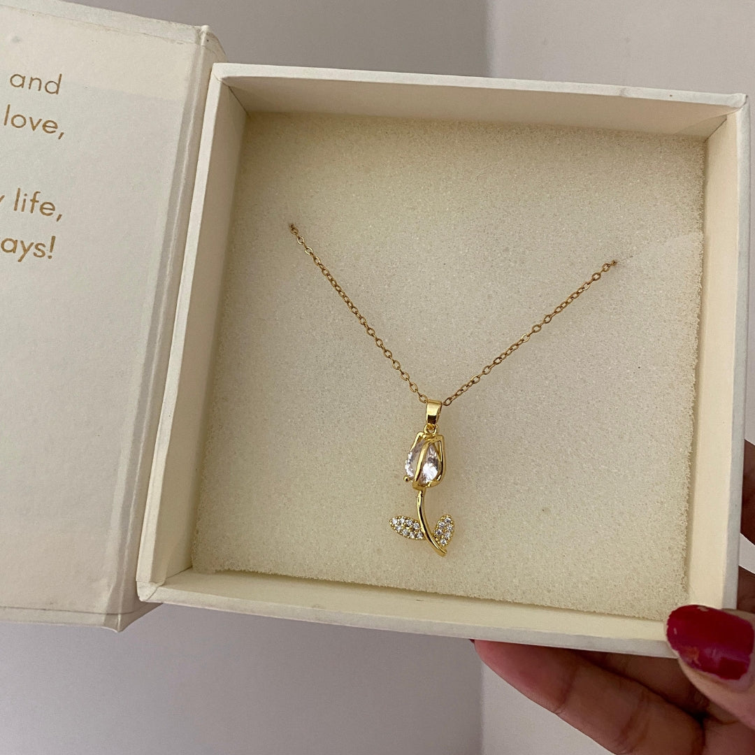  Close-up of a tulip pendant with a clear stone bloom and stone-set leaves on a gold-tone chain